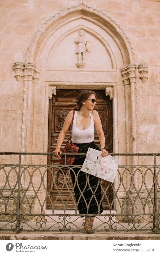 Weibliche Touristin mit Stadtplan bei der Kirche San Francesco d'Assisi in Ostuni, Italien Frau Papier Schifffahrt Regie Tourismus Sommer Ansicht Stadtbild