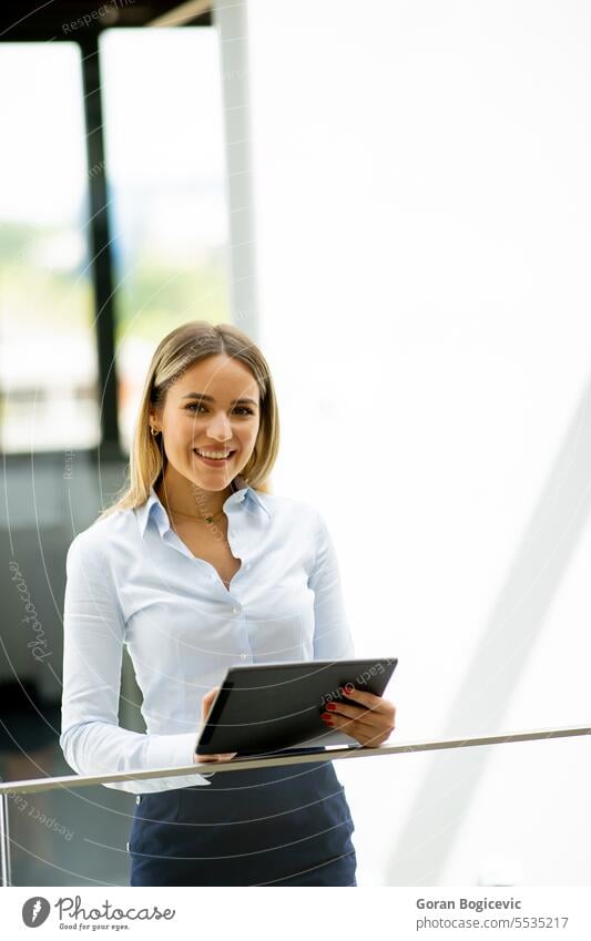 Junge Frau mit digitalem Tablet im modernen Büroflur stehend Erwachsener attraktiv schön Business Geschäftsfrau lässig heiter Mitteilung Unternehmen