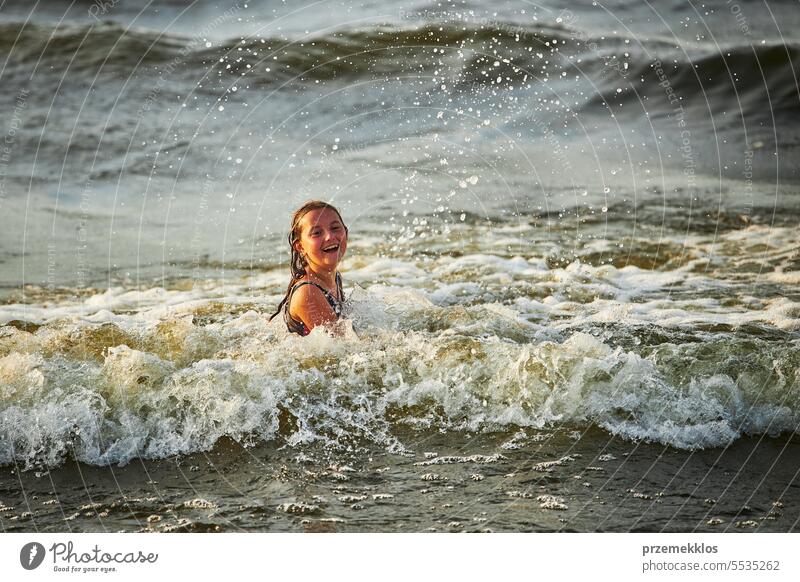 Kleines Mädchen spielt mit Wellen im Meer. Kind plantscht spielerisch mit Wellen. Kind springt in Meereswellen. Sommerurlaub am Strand Ferien MEER Spielen