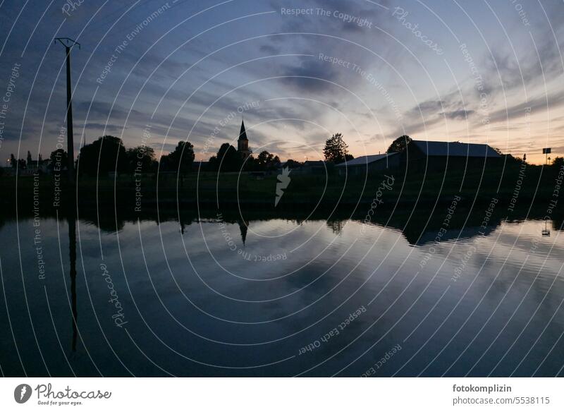 Abendstimmung Himmel und Wasser _ Skyline eines Dorfes spiegelt sich im Gewässer Kirchturm silouette Architektur Kirchturmspitze Mast Strommast Abenddämmerung