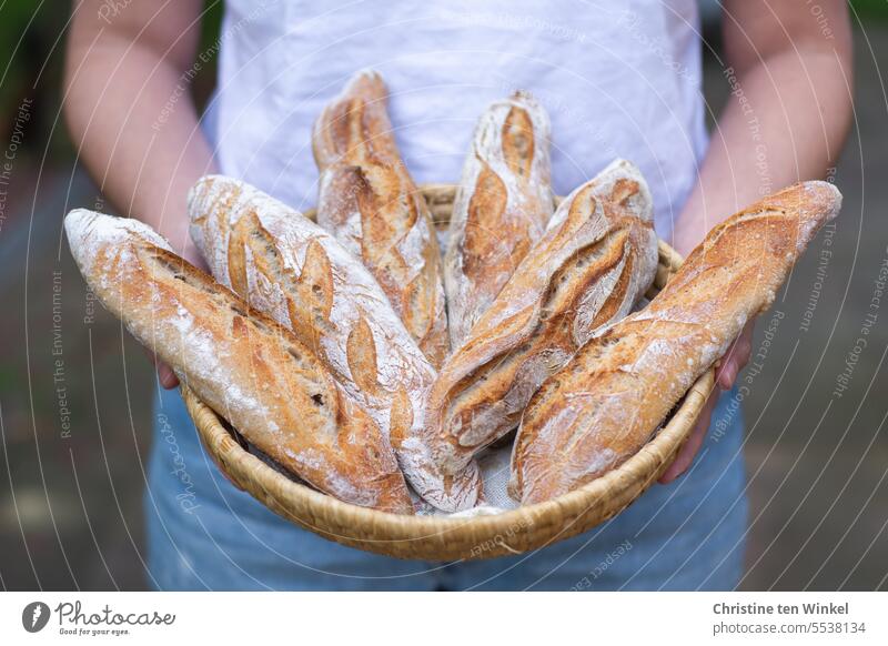 Die junge Frau präsentiert stolz die hausgemachten Baguettes rustikal Brotkorb Tradition Kruste knusprig schmackhaft köstlich aromatisch frisch geschmackvoll