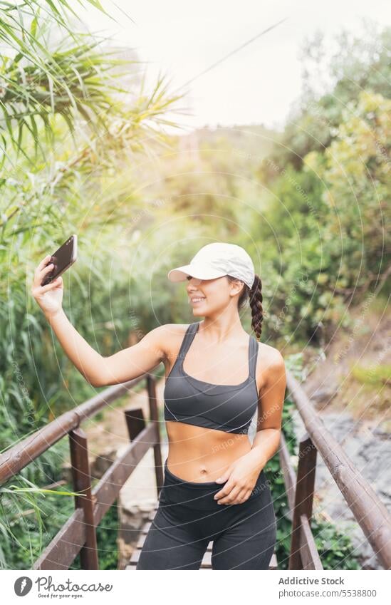 Weiblicher Wanderer macht Selfie im Wald Frau Lächeln Pause ruhen Wochenende reisen Smartphone Wälder Glück Hut Selbstportrait froh Reisender Baum Natur Mobile