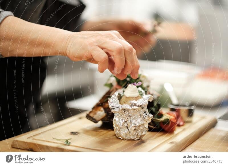 Rippenbraten vom Rind frisch von der Köchin in der Küche zubereitet mit Wildkräutern Ofenkartoffel und Karotten Küchenkräuter Küchenchef Küchenbrett zubereiten