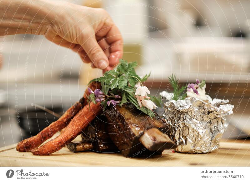 Rippenbraten vom Rind frisch von der Köchin in der Küche zubereitet mit Wildkräutern Ofenkartoffel und Karotten kochen & garen Küchenkräuter Küchenchef Koch