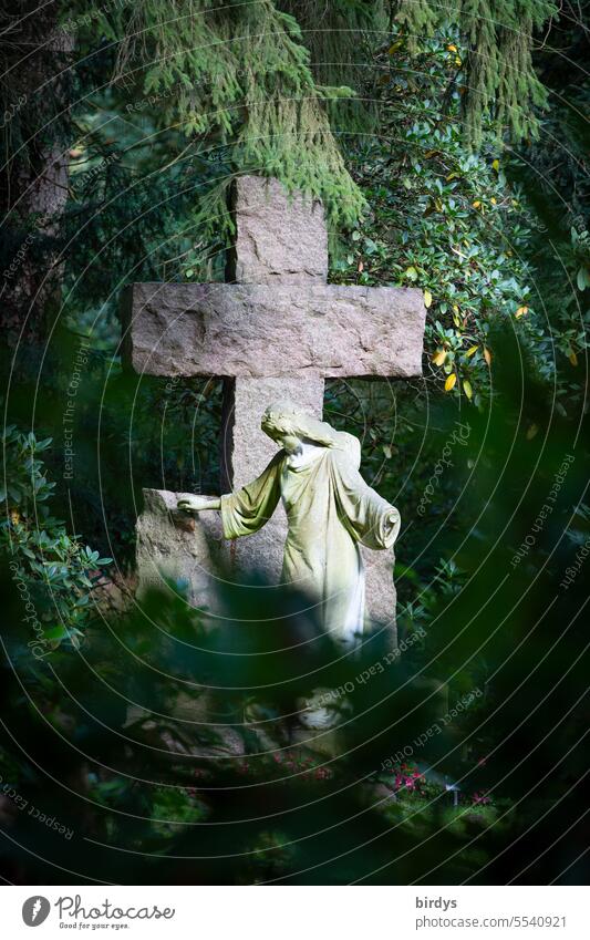 biblische Frauenstatue vor steinernem Kreuz Steinkreuz Christliches Kreuz Religion & Glaube Christentum Engel Tod Trauer Friedhof Bäume Pflanzen Spiritualität