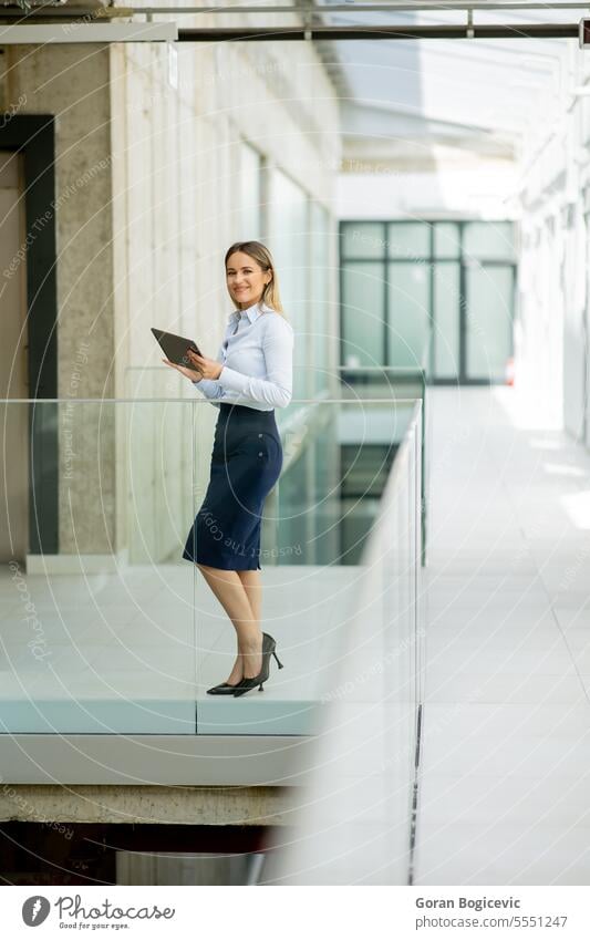 Junge Frau mit Digital-Tablet zu Fuß in der modernen Büroflur Erwachsener attraktiv schön Business Geschäftsfrau lässig heiter Mitteilung Unternehmen