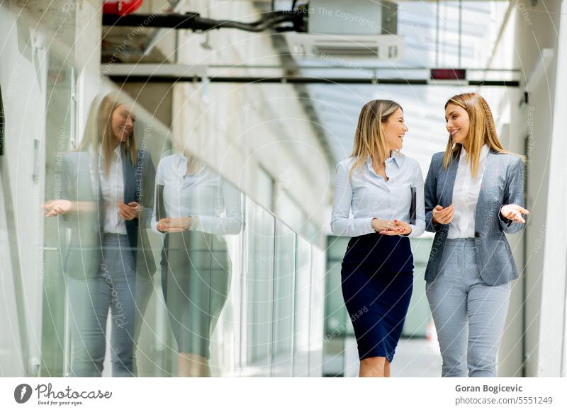 Zwei junge Geschäftsfrauen gehen im Büroflur spazieren und unterhalten sich Erwachsener Business Geschäftsmann Geschäftsleute kaukasische Ethnizität