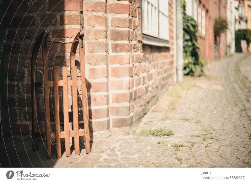 Ein Schlitten im Sonnenschein Sommer Sonnenlicht Winter stehen Hauswand Altstadt Gasse historisch alt Kopfsteinpflaster Gebäude Straße Holzschlitten Wand Stadt