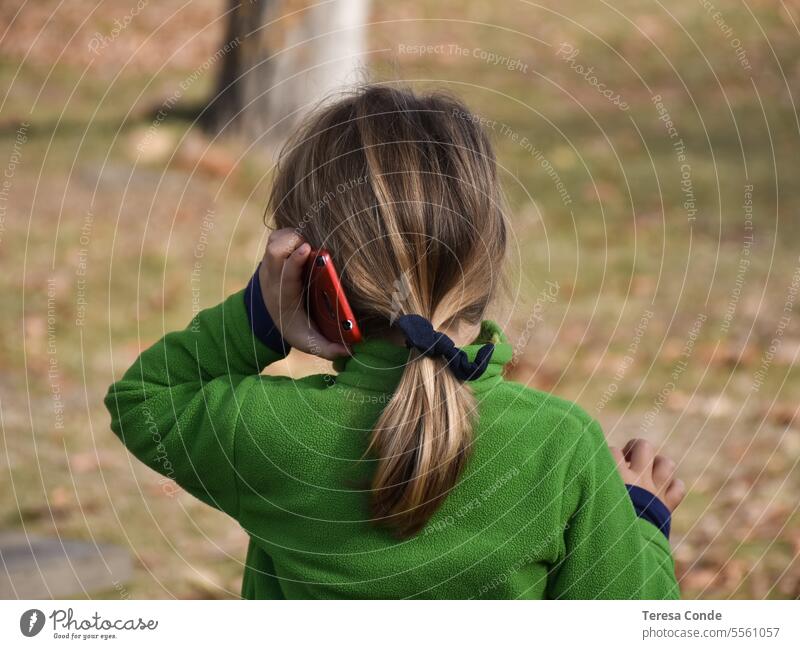 Mädchen mit blonden Haaren und Pferdeschwanz spielt mit Handy. Spielen im Freien Telefon Kind Smartphone Mobile Internet spielen Gerät online jung benutzend