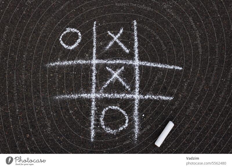 Tic-Tac-Toe-Spiel mit weißer Kreide auf Asphalt gezeichnet.  Zeichnung auf dem Bürgersteig. Straßenbelag Buntstifte Kindheit Tag kreisen durchkreuzen Form Wahl