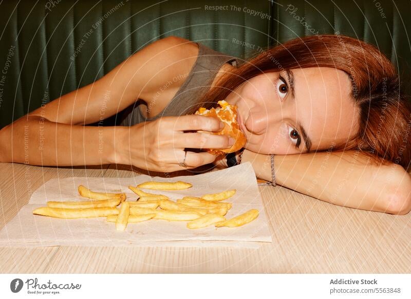 Junge Frau isst gerne Hamburger Mädchen essen Fastfood Burger jung Lebensmittel Tisch Sitzen eine Abendessen Mittagessen Snack Beteiligung Hand ungesund