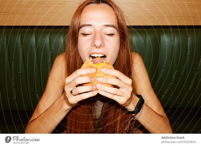 Junge Frau isst gerne Hamburger Mädchen essen Fastfood Burger jung Lebensmittel Tisch Sitzen eine Abendessen Mittagessen Snack Beteiligung Hand ungesund