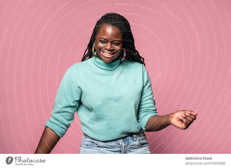 Fröhliche, lachende Afrikanerin im blaugrünen Pullover Afrikanisch Frau Lachen rosa Hintergrund freudig Fröhlichkeit Emotion echte Lächeln Zähne Geflecht Frisur