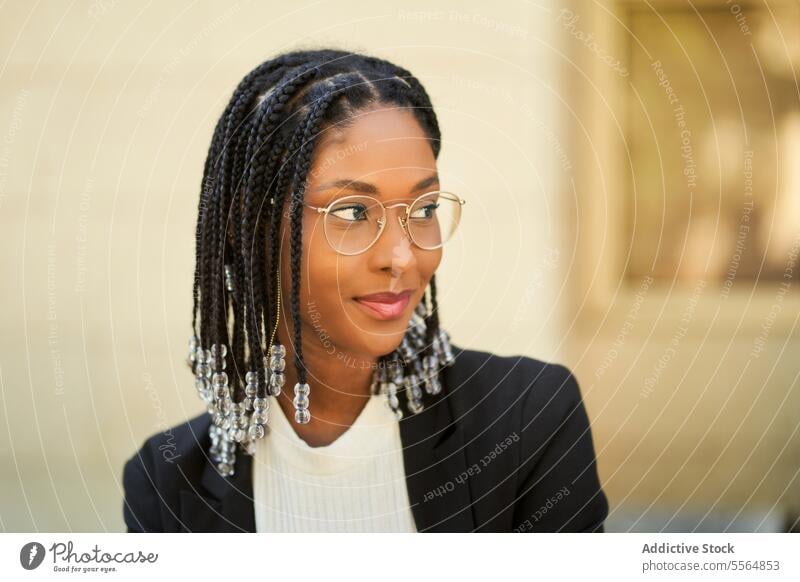 Lächelnde stilvolle afroamerikanische Frau vor einem unscharfen Hintergrund Stil Geschäftsfrau selbstbewusst Outfit Gebäude urban modern positiv Unternehmer