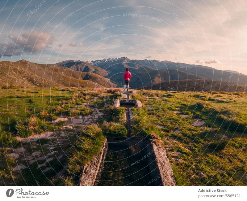 Ein Mann in einem grasbewachsenen Feld mit Bergen im Hintergrund Kanal Wasser grasbewachsenes Feld Gredos Spanien Natur Landschaft im Freien malerisch ländlich