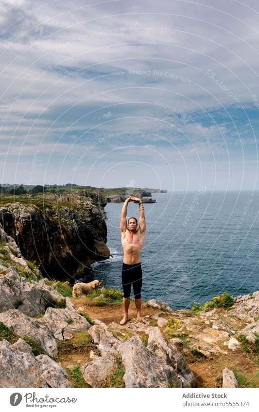 Meditativer Moment auf der Klippe Mann Yoga Pose Meer Hund Meditation Natur ruhig Achtsamkeit Küstenlinie Meereslandschaft Frieden Erholung Fokus Gleichgewicht