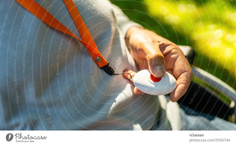 Ältere Person drückt Notrufknopf in seiner Hand draußen in einem Rollstuhl. Notrufsystem Konzept Bild. medizinisch Alarmanlage Alarmtaste Senior älter Panik