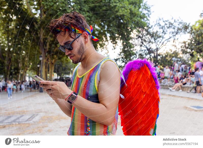 Junger Mann engagiert in Stolz Feier lgbtq Regenbogen Telefon Flügel farbenfroh Sammeln im Freien Stadtfest Veranstaltung Text Nachricht Menge