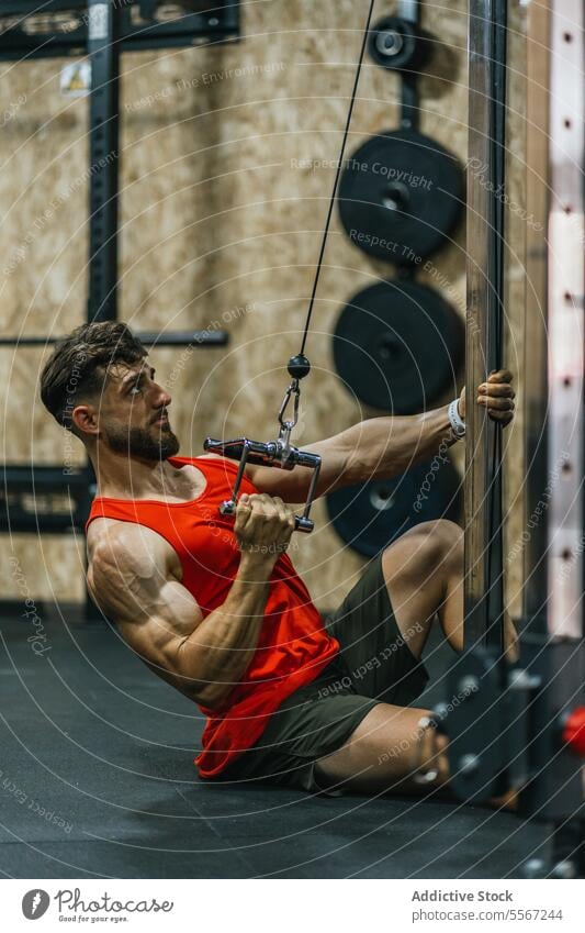 Intensives Kabel-Workout Mann Fitnessstudio Abrufbar unter Übung Tank Top Muskel Stärke Gerät Ober... Körper Griff Maschine Gewicht Teller Holz Wand Intensität