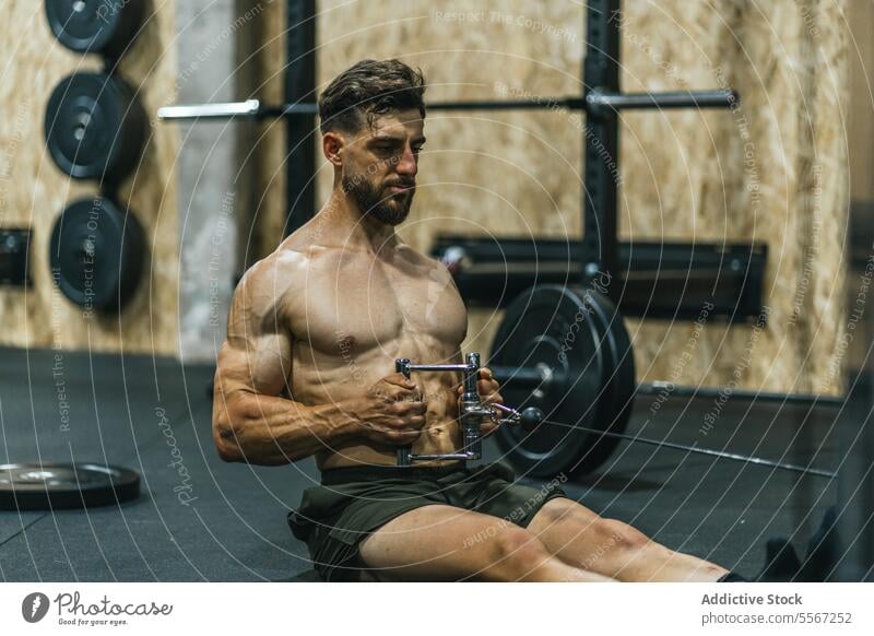 Kabelkonzentration in der Turnhalle Mann Fitnessstudio Training Muskel grün Shorts sitzend Stock Fokus Gerät Hantelscheibe Bank Wand Intensität Übung ziehen