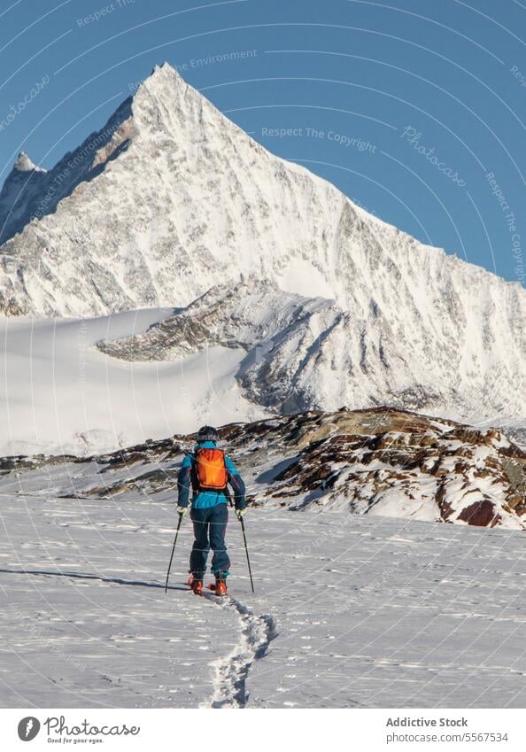 Person mit Skistöcken auf einem schneebedeckten Berg im Urlaub Ganzkörper Rückansicht unkenntlich Mast laufen Schnee deckend Berge u. Gebirge sonnig Abenteuer