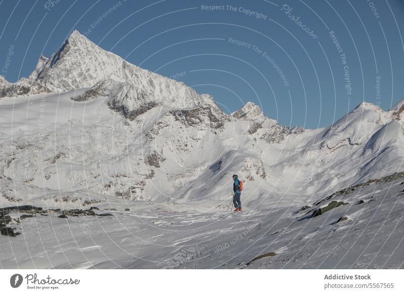 Person mit Skistöcken auf einem schneebedeckten Berg im Urlaub Ganzkörper Rückansicht unkenntlich Mast laufen Schnee deckend Berge u. Gebirge sonnig Abenteuer