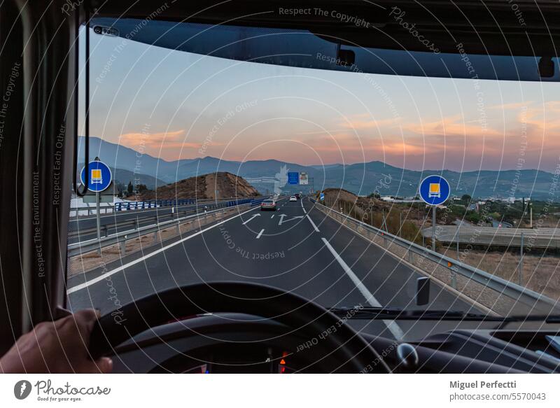 Blick aus dem Inneren eines Lastkraftwagens auf einige Verkehrsschilder, die darauf hinweisen, dass die Straße, auf der er verkehrt, für die Beförderung gefährlicher Güter zugelassen ist.