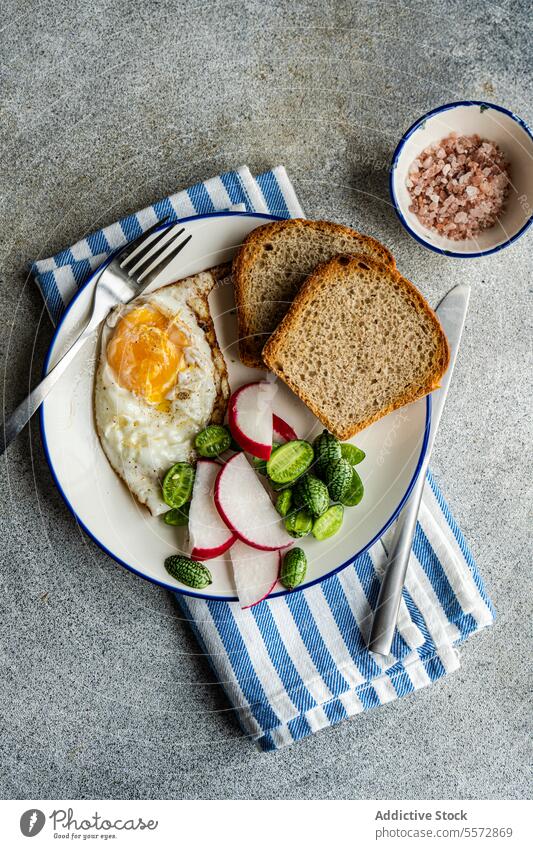 Gesunder Mittagsteller auf gestreiftem Tuch Frühstück Ei Brot Rettich Gemüse grün Stoff blau weiß Schalen & Schüsseln rosa Salz grau Textur Hintergrund Teller