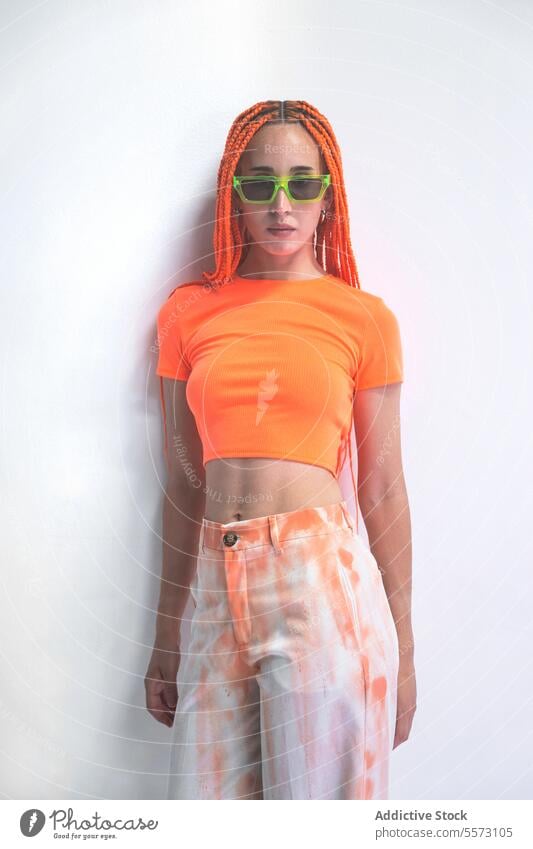 Frau mit orangefarbenen Zöpfen auf weißem Hintergrund schön jung selbstbewusst stylisch Zopf Mode weißer Hintergrund posierend Sonnenbrille Porträt Model