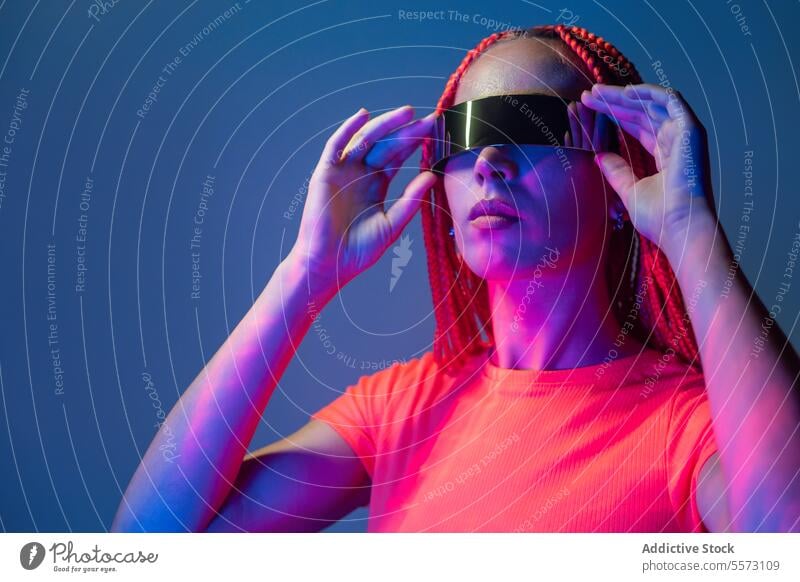 Frau mit futuristischer VR-Brille im Studio Schutzbrille Erfahrung virtuell Realität Frisur Studioaufnahme Licht erweitert Cyberspace Innovation Simulator