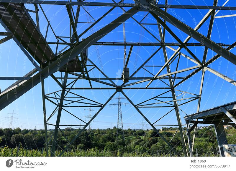 Blick durch einen Strommast auf einen weiteren Strommast Stromkabel Elektrizität Energie Kraft Himmel Spannung Leitung Kabel Draht Mast Technik Stahl Metall