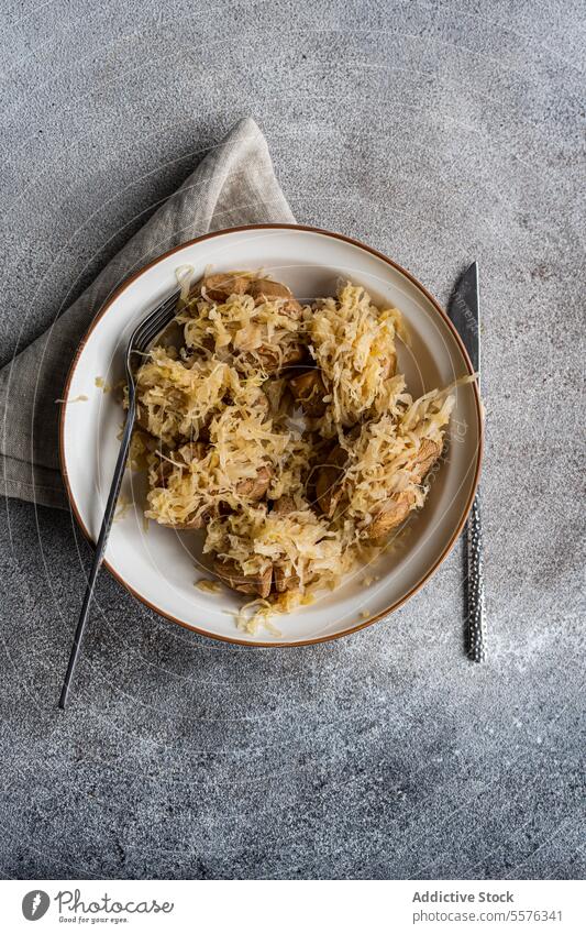 Pellkartoffel mit fermentiertem Kraut Teller Kartoffel Kohlgewächse Salatbeilage Gabel Messer grau Oberfläche Stoff Serviette Textur Mahlzeit Speise Belag