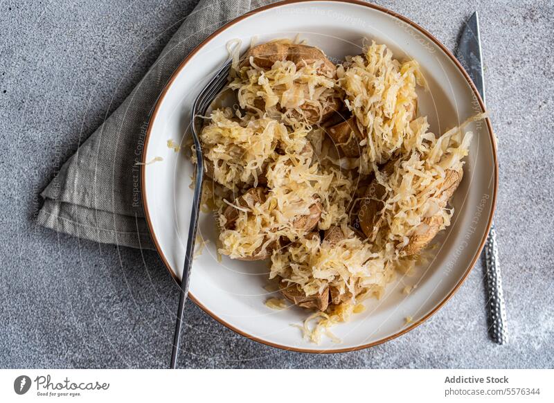 Pellkartoffel mit fermentiertem Kraut Teller Kartoffel Kohlgewächse Salatbeilage Gabel Messer grau Oberfläche Stoff Serviette Textur Mahlzeit Speise Belag