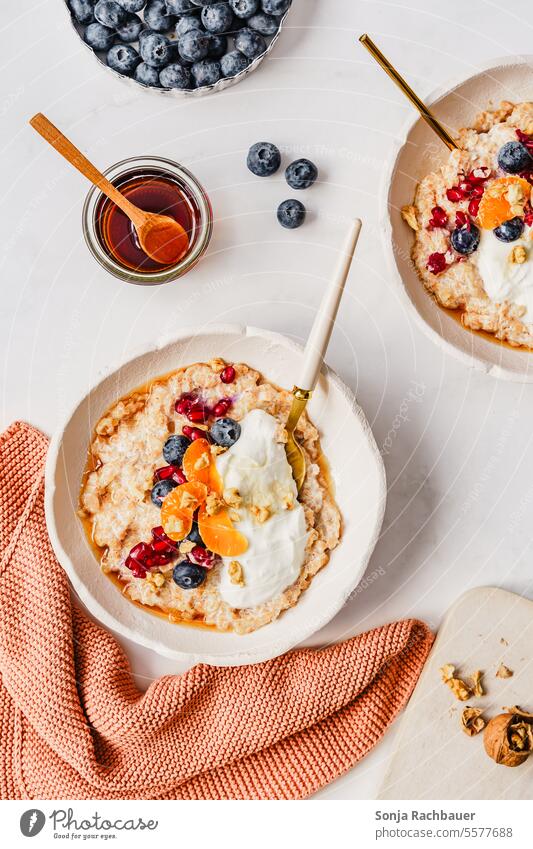 Porridge mit Früchten und Honig in zwei Schüsseln. Draufsicht. Haferflocken Frühstück Mandarine Heidelbeere Milch warm Haferbrei Gesundheit Diät