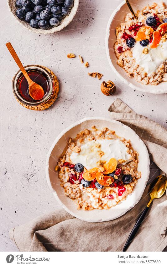 Warmer Porridge mit Mandarinen und Heidelberren in einer Schüssel. Draufsicht, Frühstück. Haferbrei warm Heidelbeere Honig Milch Schalen & Schüsseln Ernährung