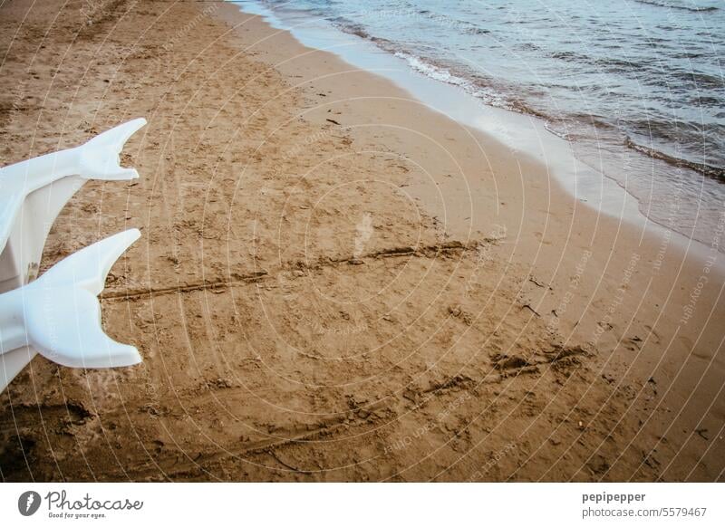 Zwei Delphin-Flossen eines Tretbootes am Strand liegend Delphine Schwimmen & Baden Meer Außenaufnahme Stranddüne Sand Sandstrand Delfin gelb Wasser