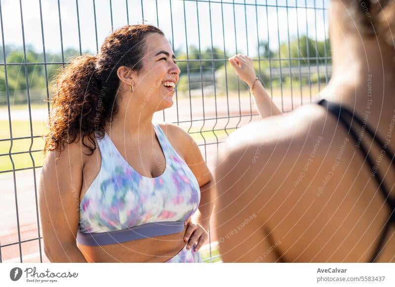 Universitätsstudentin, die sich neben einem Zaun auf der Leichtathletikbahn ihrer Hochschule ausruht und Zeit mit Freunden verbringt Lifestyle Frauen Person