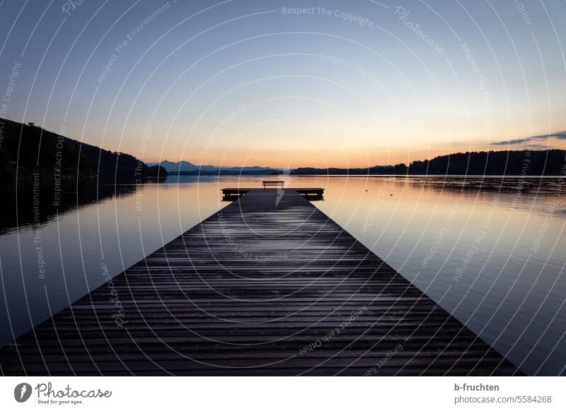 langer Holzsteg mit einer leeren Parkbank in der Abenddämmerung Wasser Steg See Landschaft ruhig Natur Idylle Seeufer Außenaufnahme Erholung Menschenleer Himmel