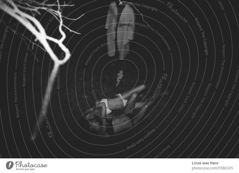 Ein Blick von einem Baum aus auf wilde, wunderschöne Mädchen, die sich küssen, und einen Mann im Bademantel, der sie einfach nur anstarrt. Es ist eine ungewöhnliche Aktivität. Es ist eine unkonventionelle Szene, in der die Dunkelheit eine unerwartete Aktivität verbirgt.