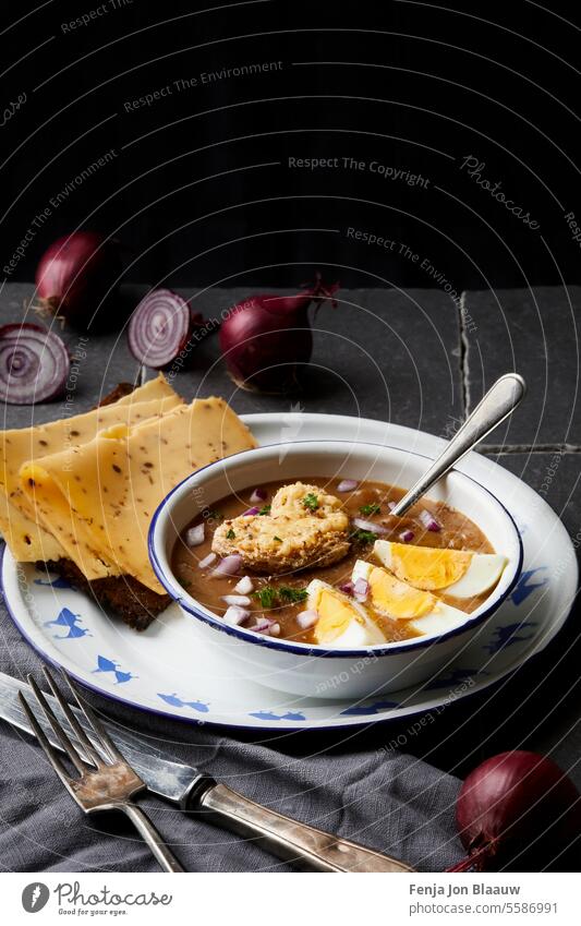 Frische gesunde Suppe mit roten Zwiebeln, serviert mit Ei und holländischem Käse Essen zubereiten geschnitten Zwiebeln schneiden dunkel und launisch