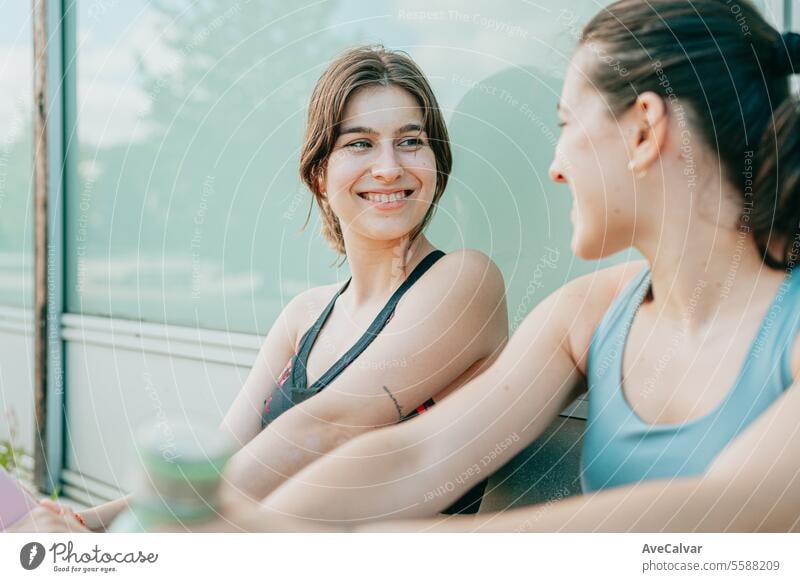 Zwei junge, fitte, fröhliche Mädchen sitzen ausgeruht nach dem Sport und freuen sich, ihre sportlichen Ziele zu erreichen. Frau Lifestyle Frauen Glück Kaukasier