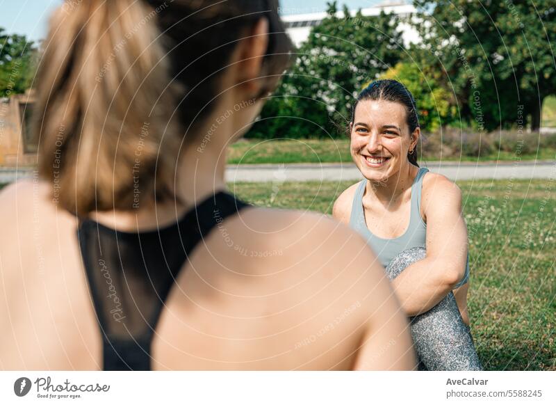 Freunde der Universität ruhen sich auf dem Rasen des Campus aus und dehnen sich, um Verletzungen nach dem Training zu vermeiden. Sport Fitness Person jung