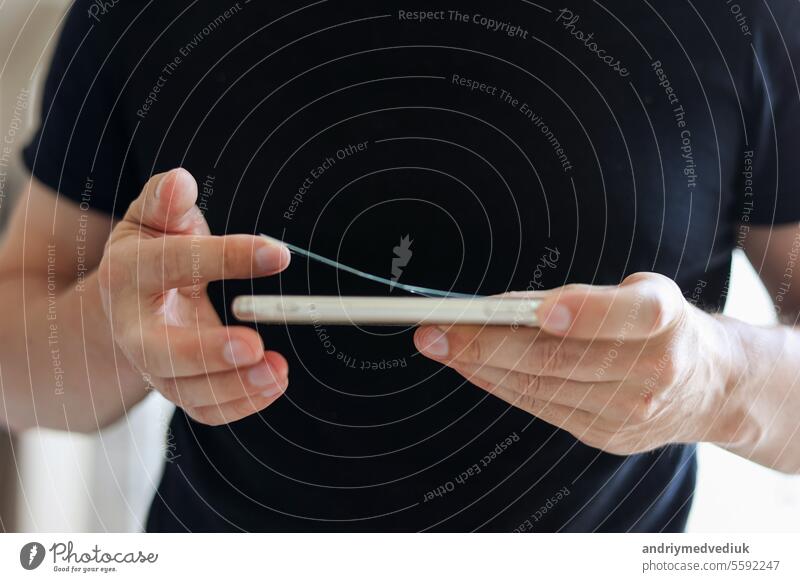 Prozess unerkennbar Techniker entfernt gebrochen und alt gehärtetem Glas Bildschirmschutz von Smartphone, Nahaufnahme. Dienstleistungen zum Kleben und Ersetzen von beschädigtem Schutzglas.