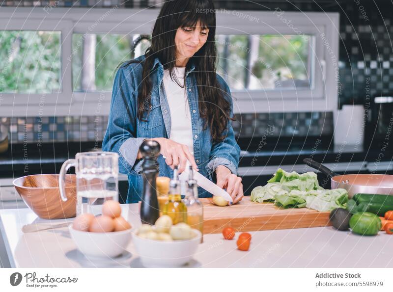 Lächelnde Frau im mittleren Erwachsenenalter bei der Zubereitung köstlicher Speisen zu Hause Avocado kleine Kartoffeln Schalen & Schüsseln Küchenchef hacken