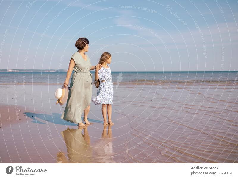 Strandspaziergang mit Mutter und Tochter Sand MEER Reflexion & Spiegelung Hut Himmel Spaziergang binden Familie Moment Frau Kind Horizont Wasser Kleid Anschluss