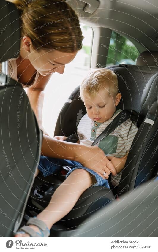 Glückliche Mutter Befestigung Sicherheitsgurte der niedlichen Kind Sohn sitzt im Autositz PKW befestigen Gurt Reise Sitz Landschaft Sommer Frau jung Junge Mama