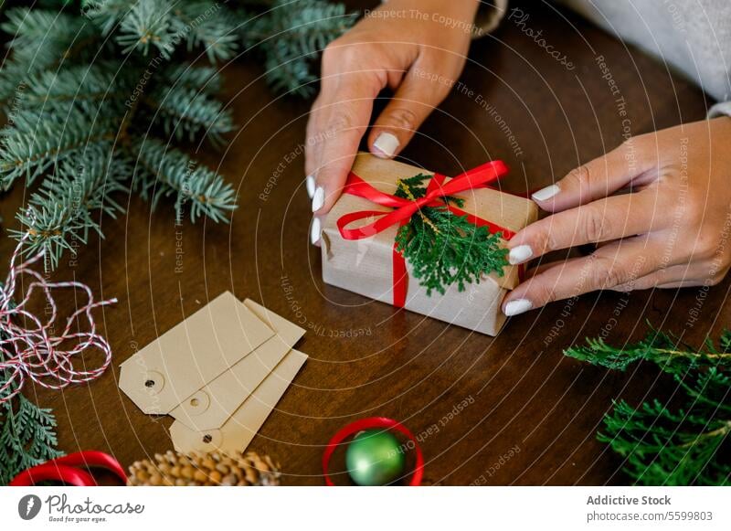 Eine unerkennbare Frau hält ein Weihnachtsgeschenk in der Hand horizontal Bändchen Person Papier dekorierend im Innenbereich Glück Schleife heimwärts