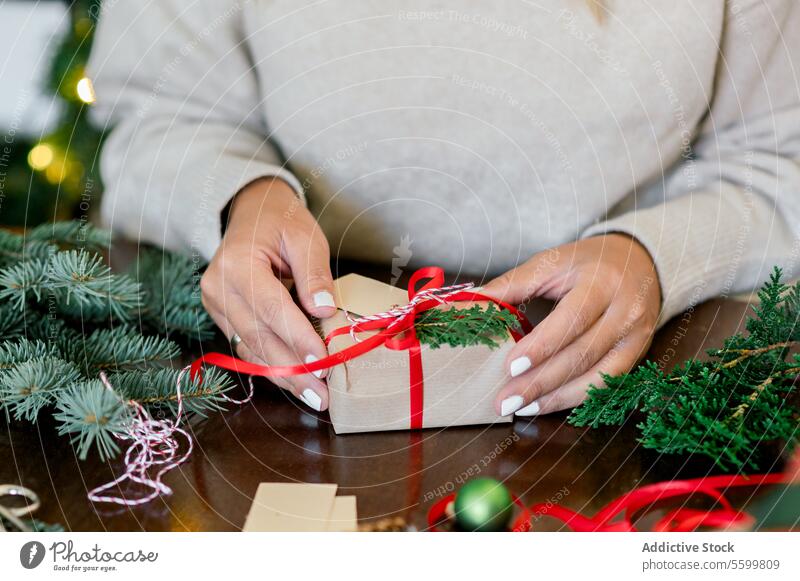 Eine unerkennbare Frau hält ein Weihnachtsgeschenk in der Hand horizontal Bändchen Person Papier dekorierend im Innenbereich Glück Schleife heimwärts