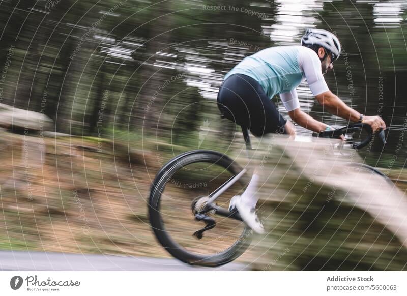 Schnelles Radfahren bergab Radfahrer Fahrrad Geschwindigkeit Bewegung Unschärfe Wald Straße Schutzhelm blaugrün Trikot im Freien Sport Fitness Natur Baum Pedal