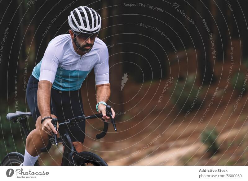 Radfahrer auf Waldweg Fahrrad drehen. Trikot weiß blaugrün Schutzhelm Konzentration im Freien Sport Straße Fitness Natur Baum Mitfahrgelegenheit männlich